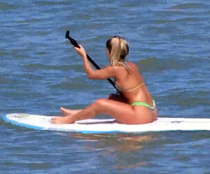 Attractive caboose in panty swimsuit on surfboard.